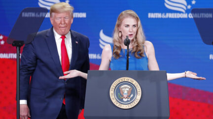 President Donald Trump, left, listens Natalie Harp, right, speak after inviting her on stage at the Faith & Freedom Coalition conference in Washington, Wednesday, June 26, 2019.