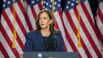 Kamala Harris standing in front of a row of US flags